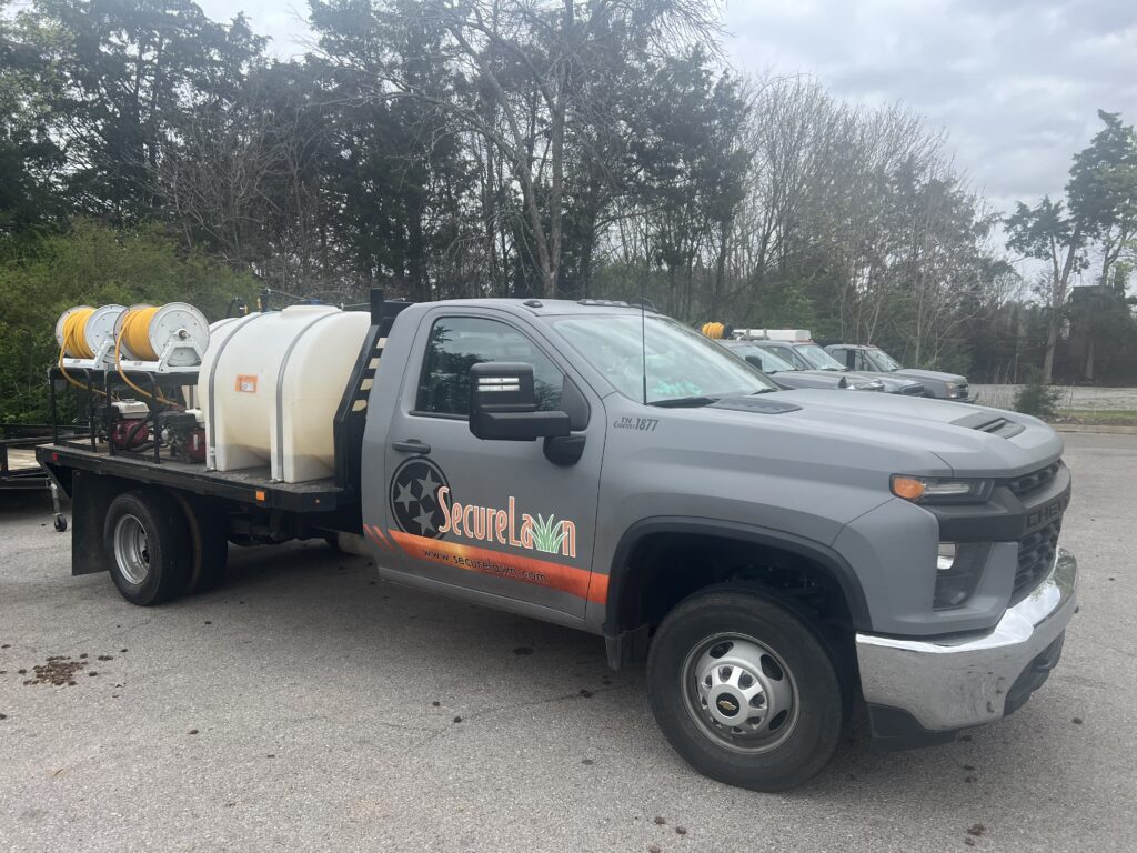 SecureLawn truck parked in a residential neighborhood, ready to provide summer insect control services with professional equipment and safe treatments.